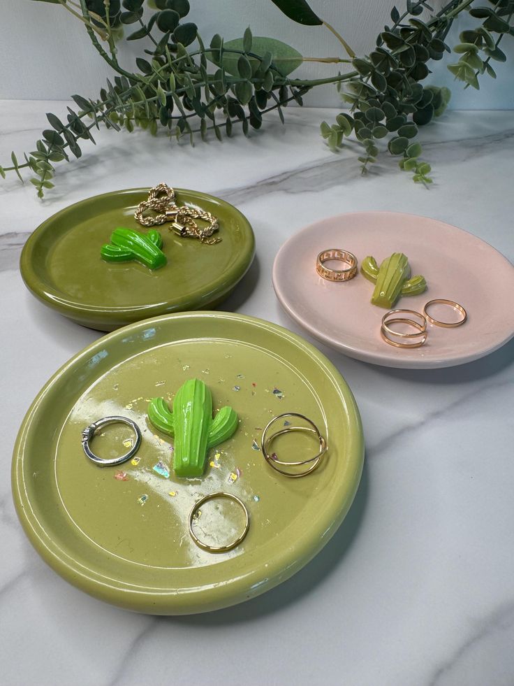 three different colored plates with rings and plants in the middle one is green, the other is pink