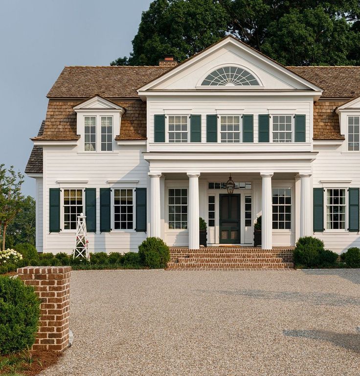 a large white house with green shutters on the front