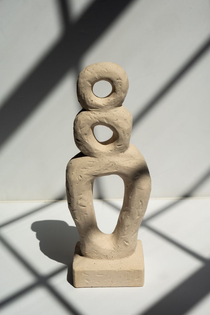 a white sculpture sitting on top of a table next to a shadow cast wall behind it