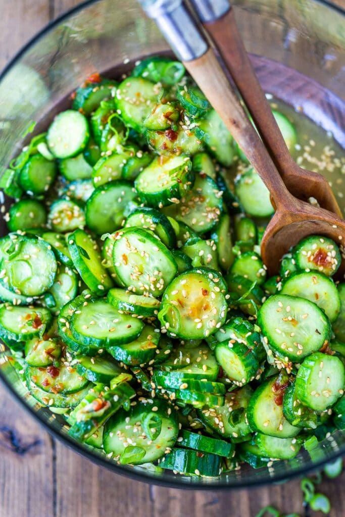 a glass bowl filled with sliced cucumbers and sesame seeds