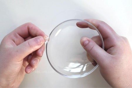 two hands are holding a clear glass bowl