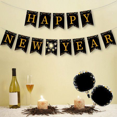 a happy new year banner with candles and wine glasses on a table next to it