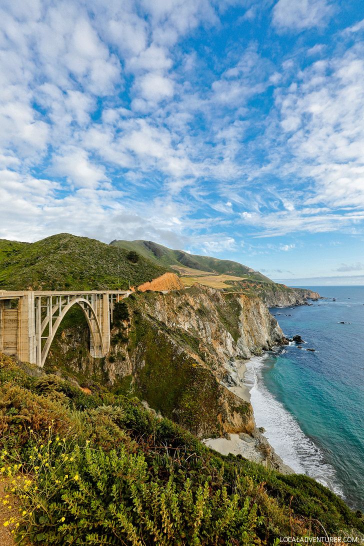 the bi - level bridge is over looking the ocean and hills on both sides, with blue skies above