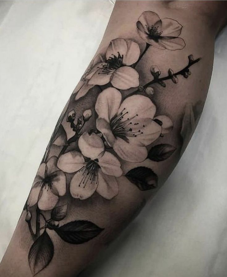 a black and white flower tattoo on the left arm, with flowers in blooming