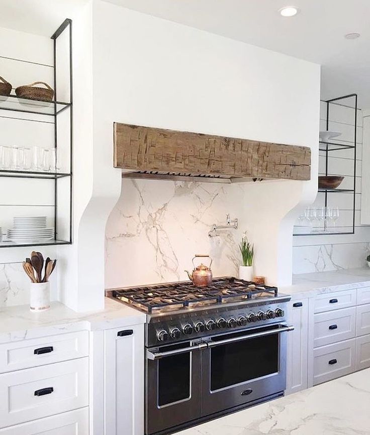 a stove top oven sitting inside of a kitchen next to white cupboards and counter tops