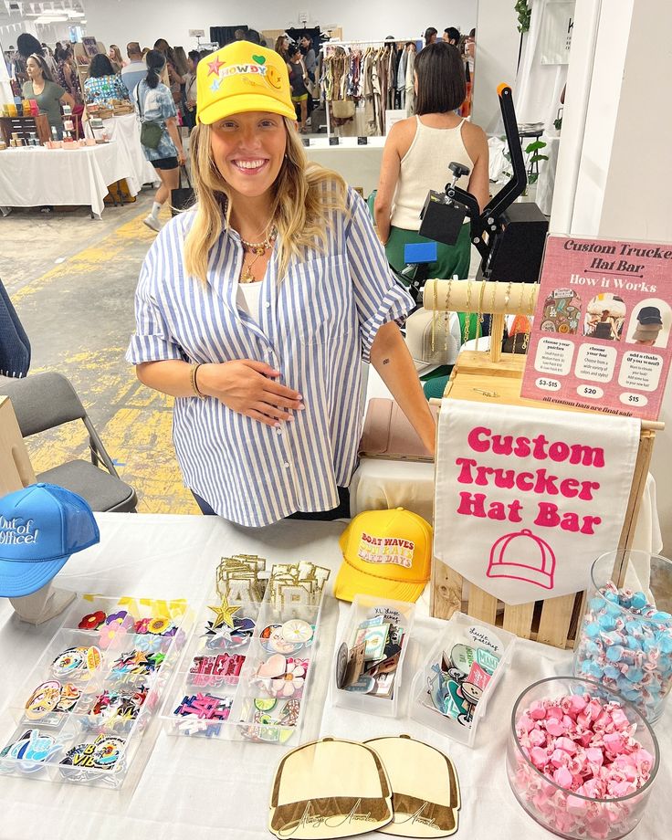 a woman standing in front of a table filled with items for sale at an event