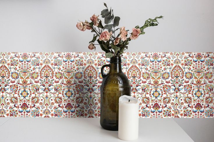 a vase filled with flowers sitting next to a bottle on top of a white table