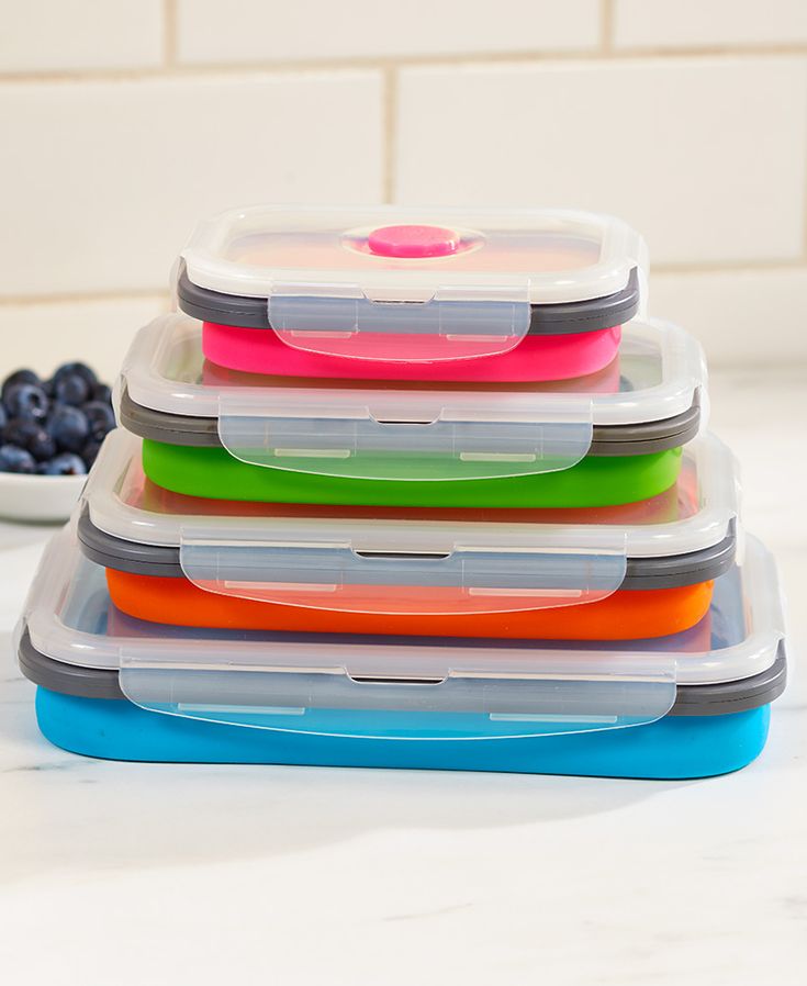 several plastic containers stacked on top of each other next to blueberries and strawberries