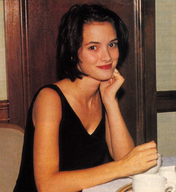 a woman sitting at a table in front of a white cup