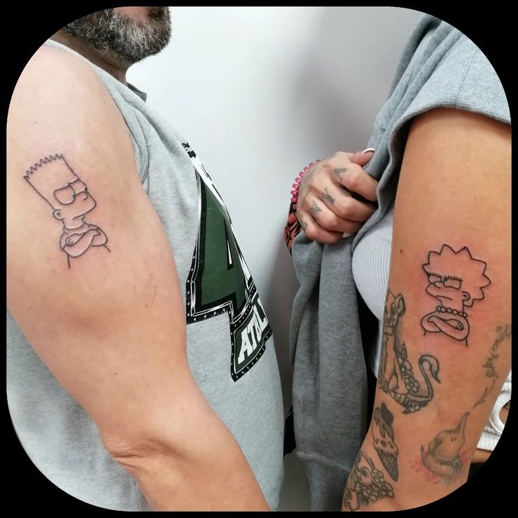 two people with tattoos on their arms and armbands, one is holding the other