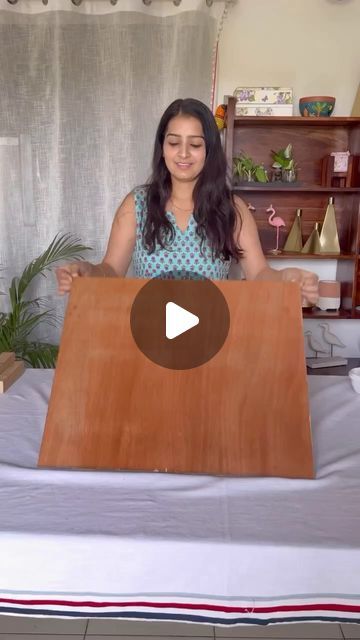 a woman sitting on top of a bed holding up a wooden sign with the word love in it