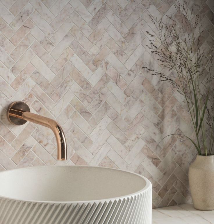 a bathroom sink with a gold faucet and marble wall tiles in the background