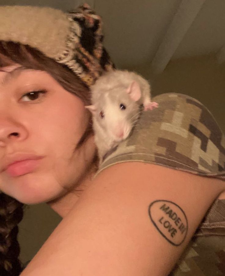 a woman with a small rat on her shoulder and the word mouse cout written on her arm