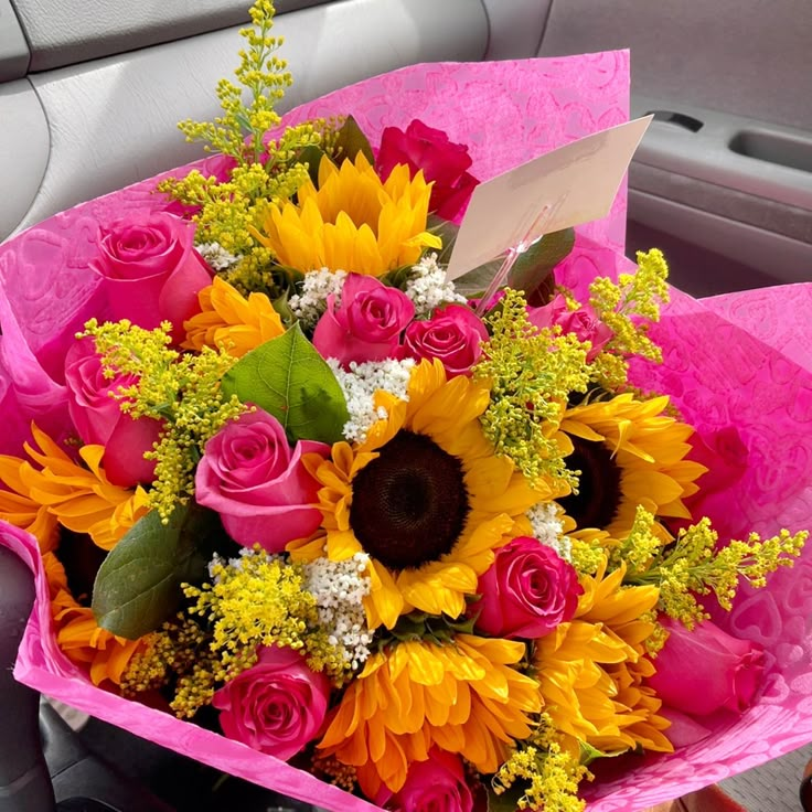 a bouquet of sunflowers and roses in a car