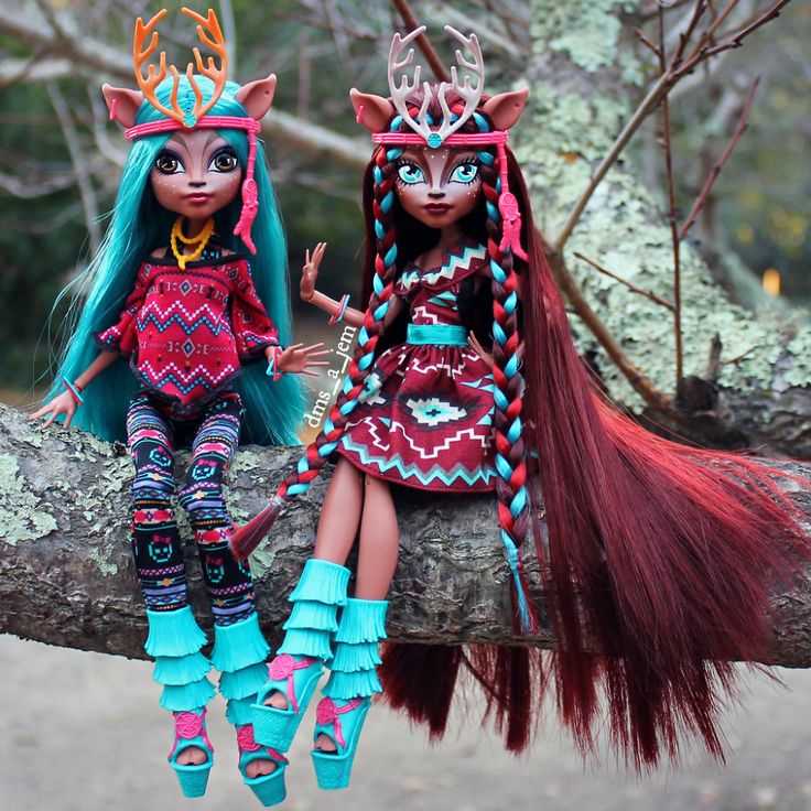 two dolls sitting on top of a tree branch