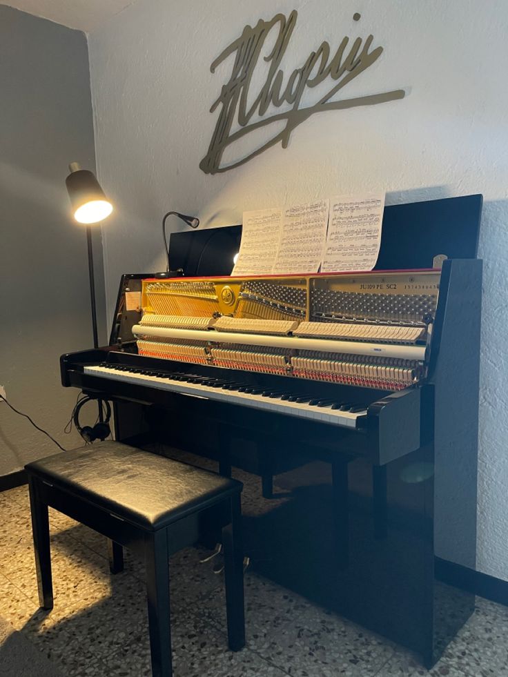 a piano sitting in front of a wall with music sheets on it's side