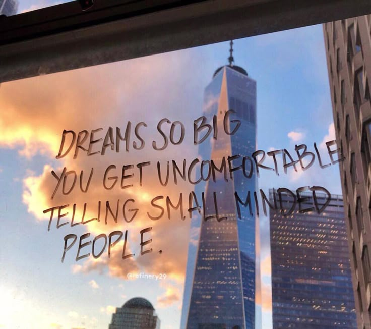 there is a message written on the window in front of skyscrapers that say, dreams so big you get uncomfortableable telling small minds people