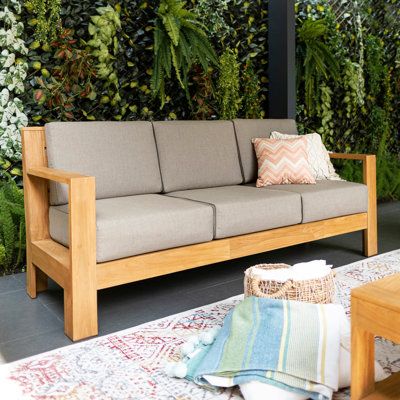 a couch sitting in front of a living room filled with greenery on the wall