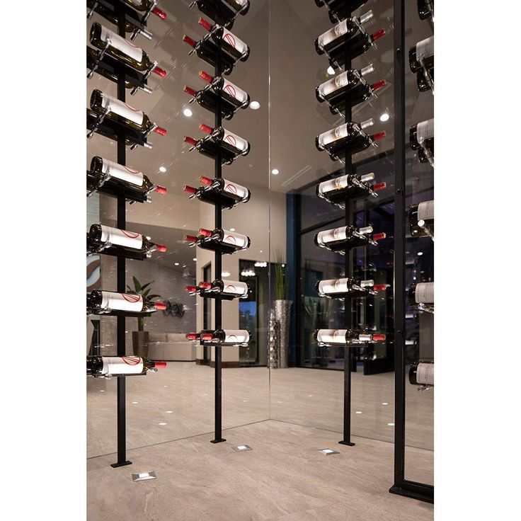 a room filled with lots of bottles of wine on top of metal poles in front of a glass wall