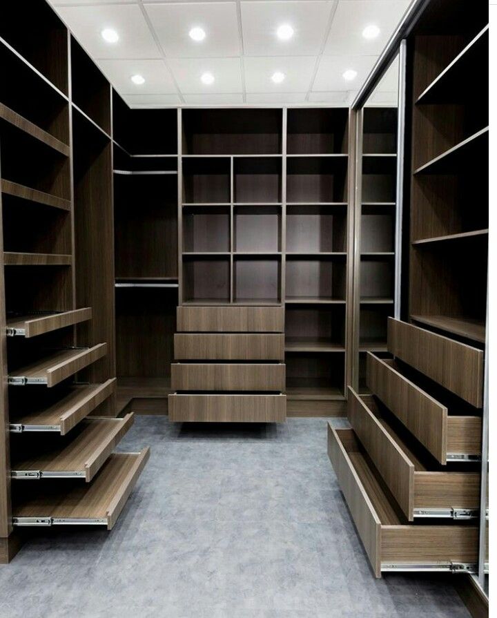 an empty walk in closet filled with lots of wooden shelves and open shelving units