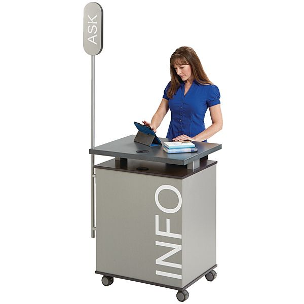 a woman standing at a desk with a laptop computer on it and an ineo sign behind her