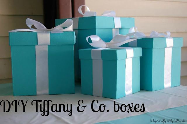 four blue boxes with white ribbons and bows on them are sitting on a table in front of a house