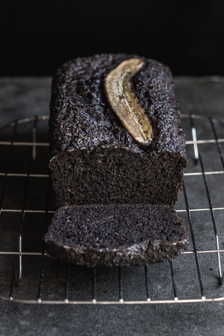 a loaf of chocolate cake sitting on top of a cooling rack next to a banana