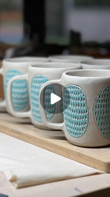 three coffee mugs sitting on top of a wooden table in front of a computer monitor