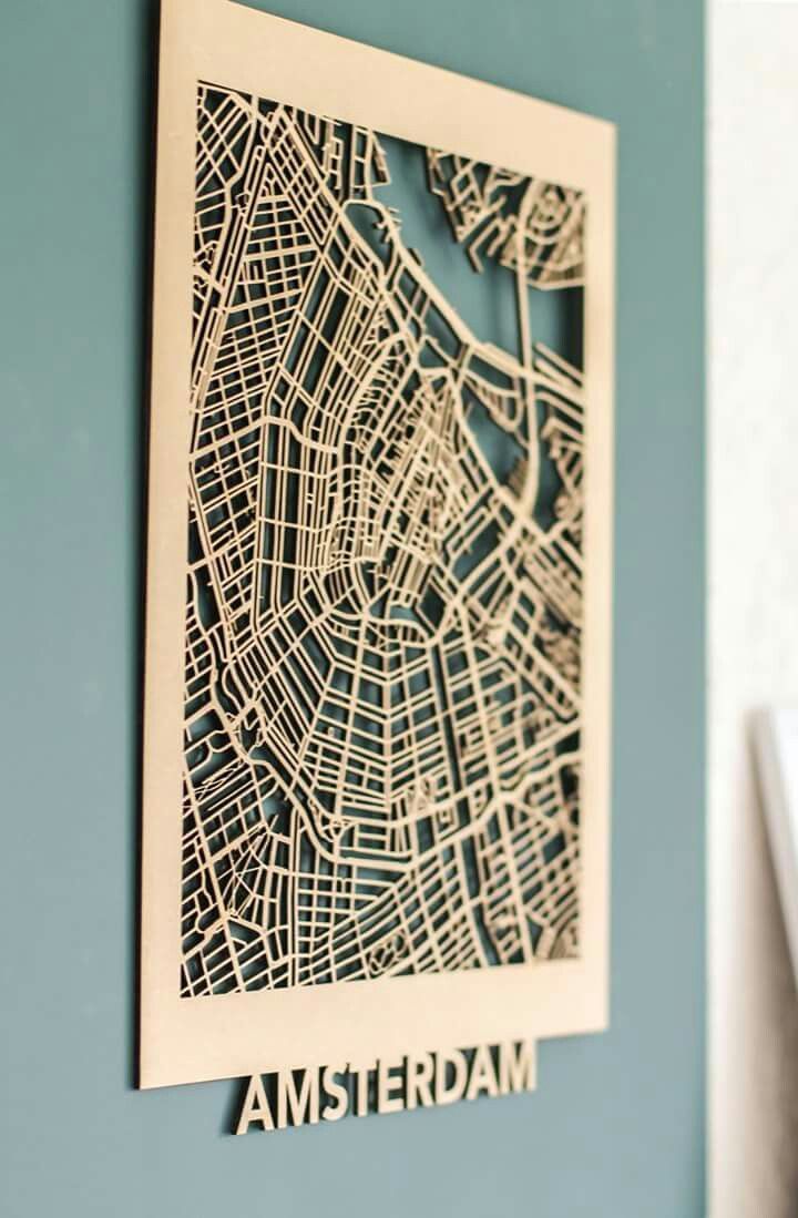 a paper cut map of amsterdam is hanging on the wall in front of a blue wall