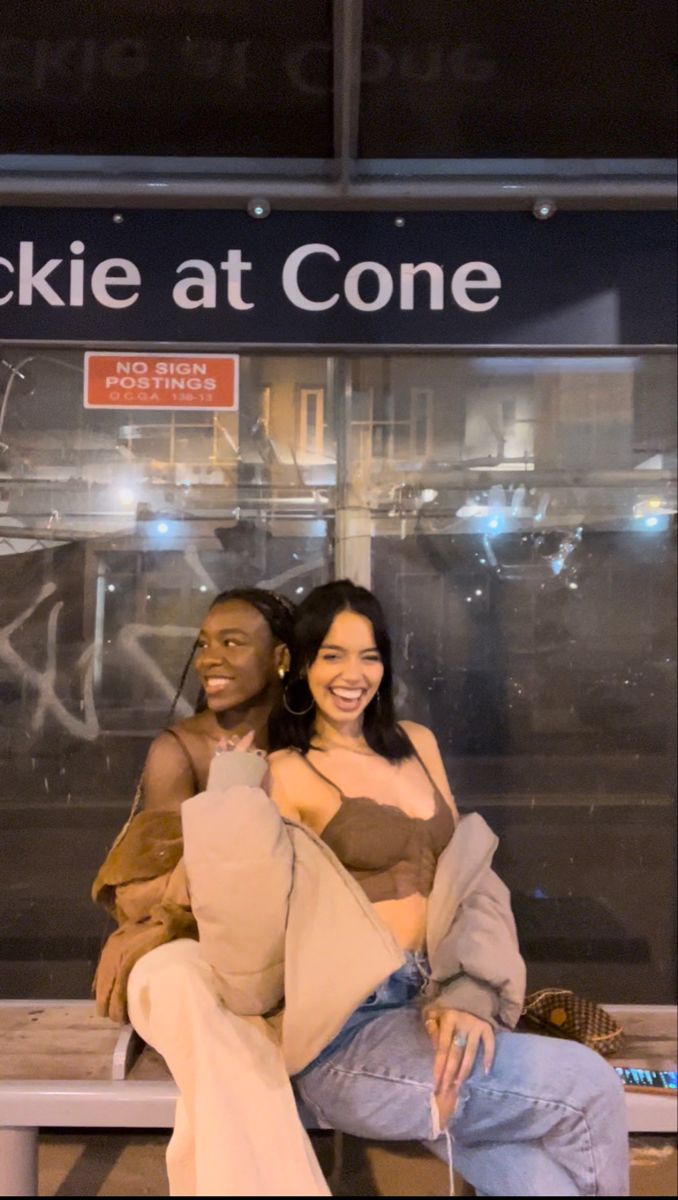 two people are sitting on a bench in front of a sign that says pickie at cone