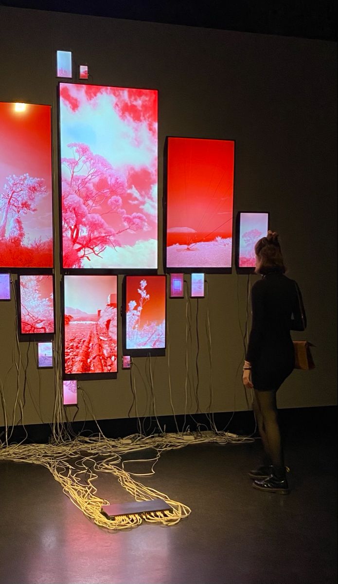 a woman standing in front of a wall with multiple screens on it