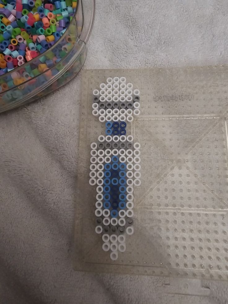 there is a lego man made out of beads on the floor next to a plastic container