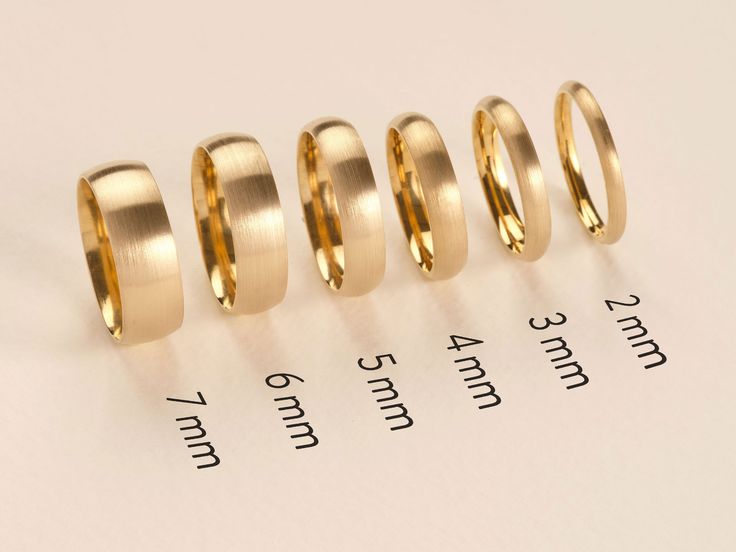 four different sizes of wedding rings sitting on top of a piece of paper next to each other