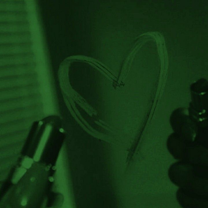 a hand holding a pen writing on a wall with a heart drawn in the background