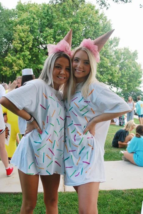 two women dressed up in costumes posing for the camera at an outdoor event with confetti on their ears