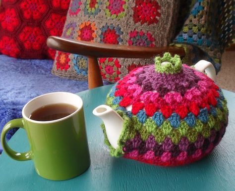 a crocheted tea pot and cup on a table with a chair in the background