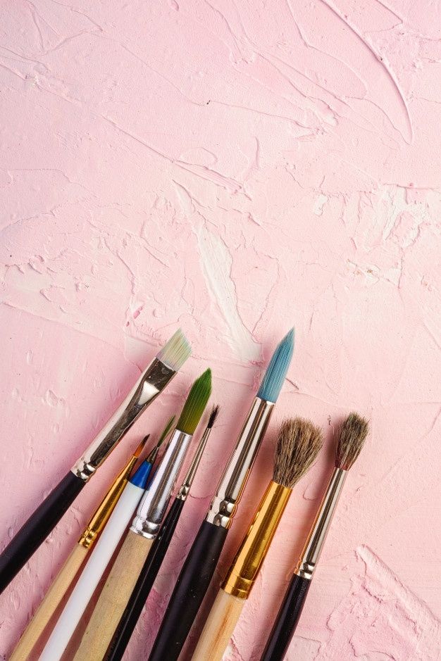 five brushes are lined up on a pink surface