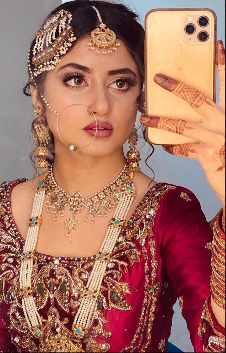 a woman is holding up her phone to take a selfie with her wedding jewelry