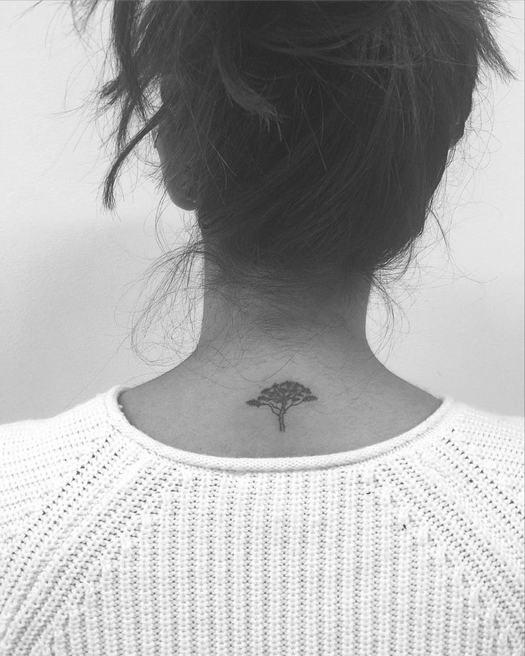 a woman with a small tree tattoo on her neck and behind her head is a white sweater