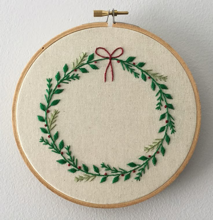 an embroidered wreath with red ribbon and green leaves