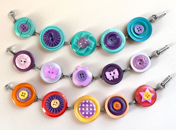 a necklace made out of buttons on a white surface with a blue and purple bead