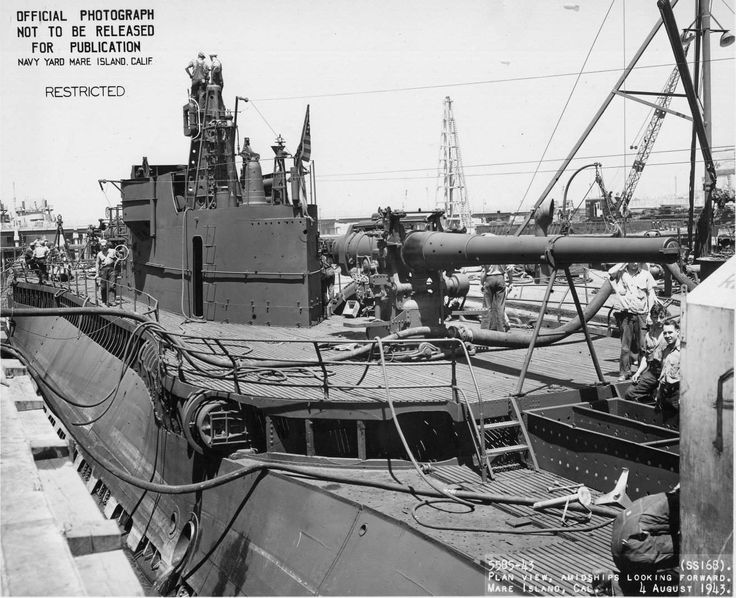 black and white photograph of ships in the water with power lines above them, some are being worked on