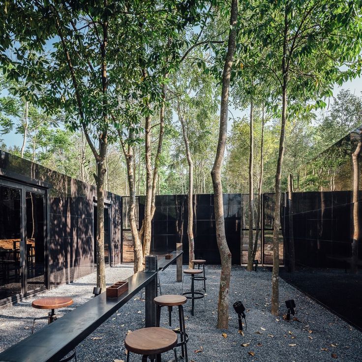 there are many tables and stools in the courtyard area with trees on both sides