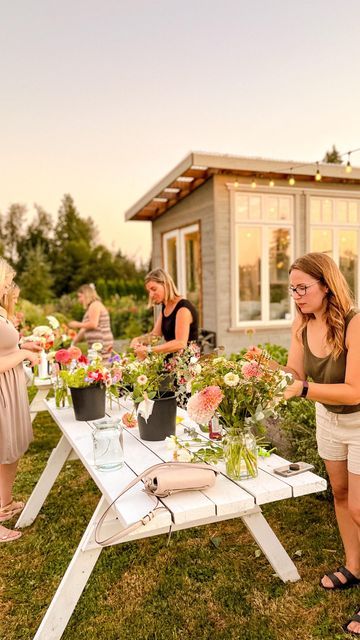 a group of people standing around a table with flowers on it in front of a house