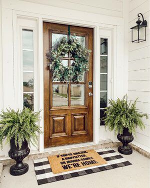 the front door is decorated with two planters and a welcome mat