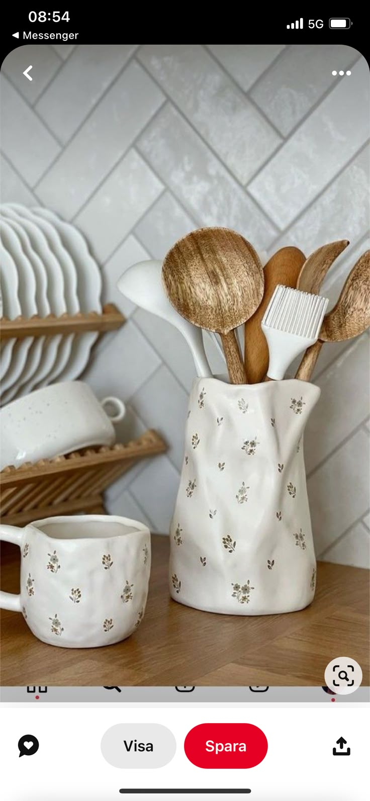 a white vase filled with spoons and spatulas on top of a wooden table