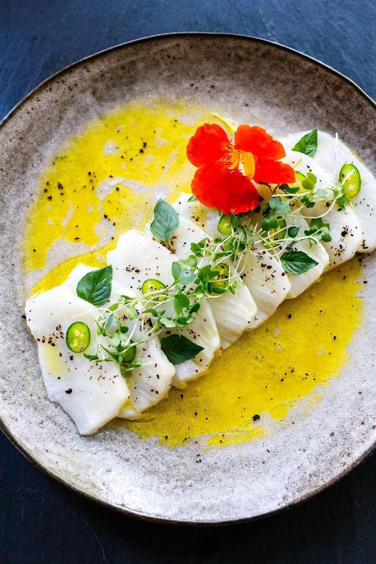 a white plate topped with fish covered in sauce and garnished with green leaves