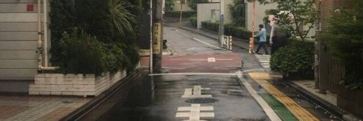 two people are walking down the street in the rain