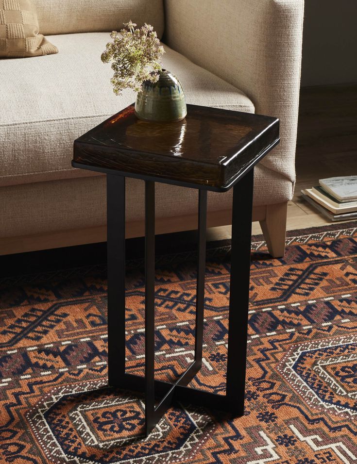 a table with a vase on top of it in front of a couch and rug