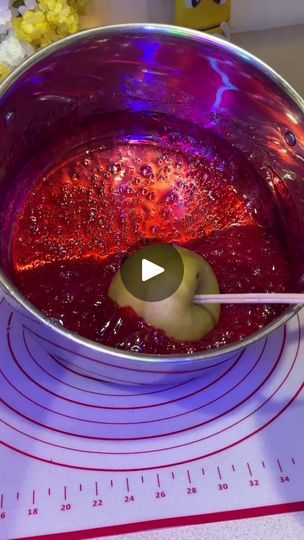 a metal bowl filled with red liquid on top of a table next to a ruler